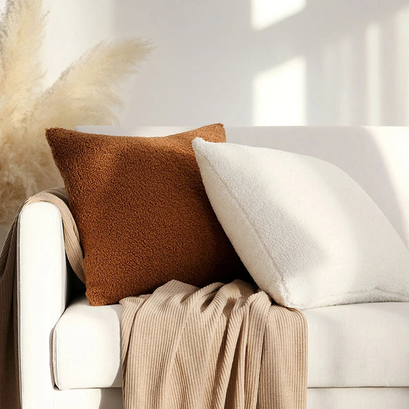 Two plush pillow covers on a couch, featuring a brown and a white cover, enhancing living room decor.