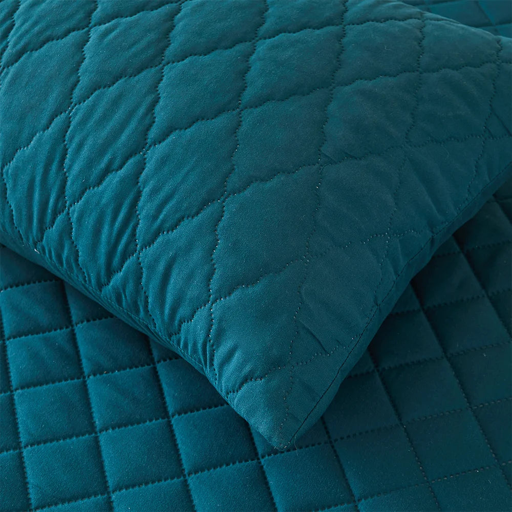 Waterproof Throw Pillowcases on a soft quilted bedding surface in teal color.